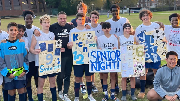 Un grupo de estudiantes celebra la Noche de Seniors en el césped de la Lawrence Woodmere Academy con carteles en las manos.