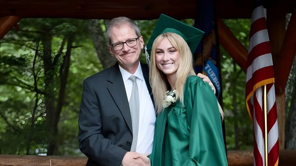 Un hombre mayor en traje está junto a una joven en vestido de graduación verde en el terreno de la Leelanau School.