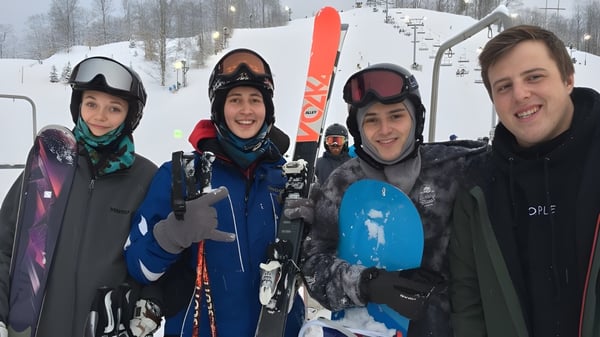 Un grupo de estudiantes de la Leelanau School está en una pista nevada equipado con casco de esquí y gafas de esquí.