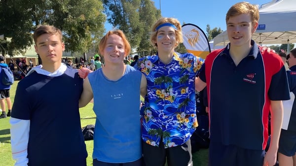 Cuatro alumnas y alumnos de la Leeming Senior High School están juntos en un campo cubierto de hierba bajo un cielo azul.