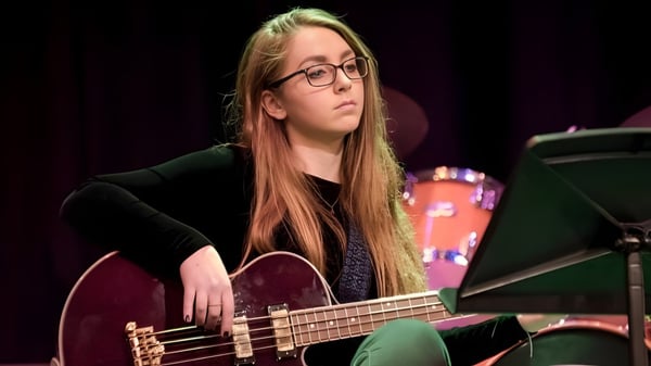 Una estudiante de la Leighton Park School toca una guitarra eléctrica en un escenario frente a equipo musical.
