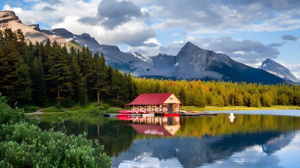 Una casa de botes roja en un lago frente a un paisaje montañoso en el terreno de la Lester B. Pearson Catholic High School.