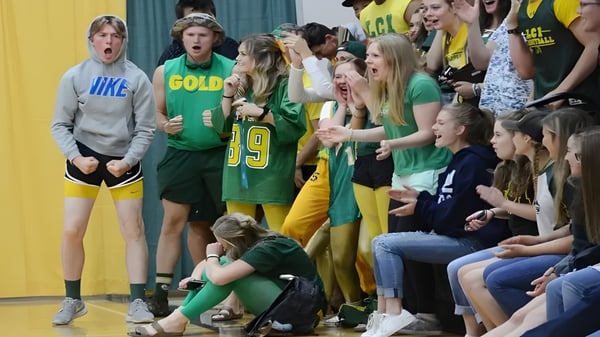 Estudiantes del Lethbridge Collegiate Institute celebran juntos en uniformes deportivos en un gimnasio.