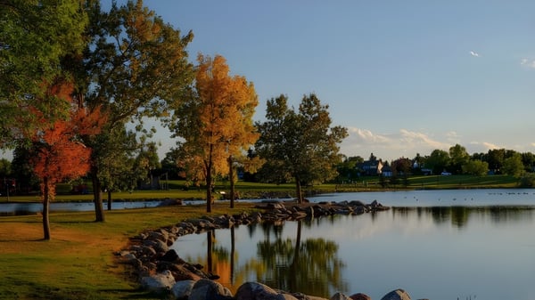 Un lago tranquilo con colores otoñales en la zona ribereña en el terreno de la Lethbridge School Division.
