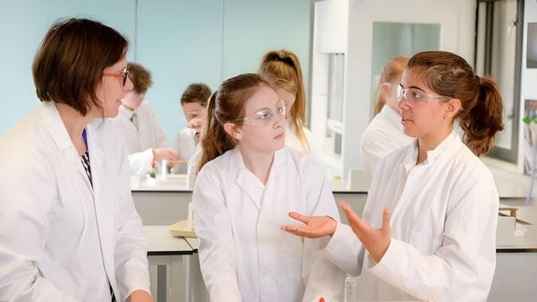 Estudiantes de la Lewes Old Grammar School discuten en bata blanca en un laboratorio.