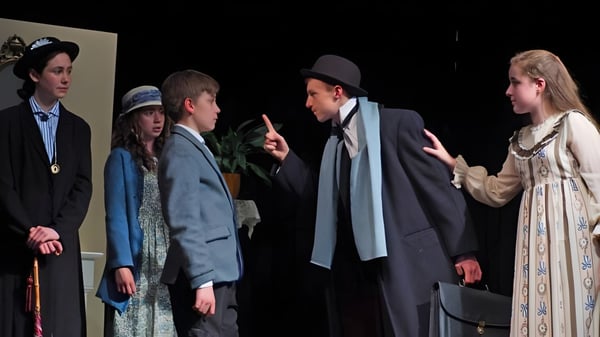 Un grupo de personas está en conversación, vestidas de manera formal e informal, en el escenario de Leweston School.