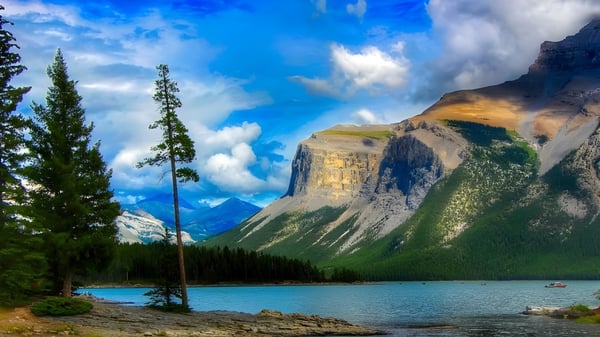 Lago de montaña con bosques perennes y acantilados rocosos bajo un cielo azul en Lewisporte Collegiate.