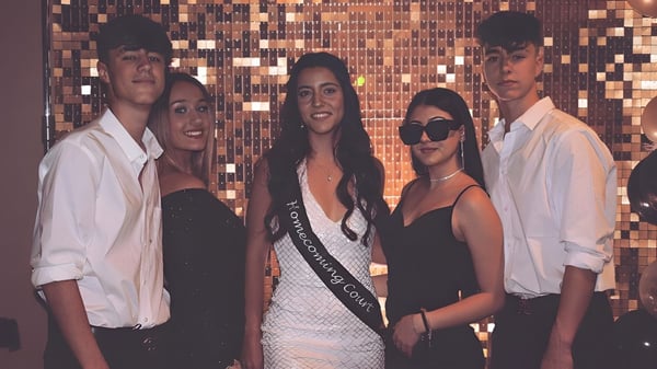 Un grupo de estudiantes de la Life Prep Academy está frente a un fondo metálico en ropa formal y casual.