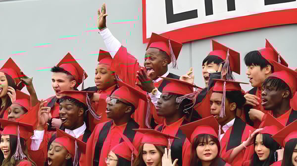 Un grupo de graduados de la Life Prep Academy en togas rojas está frente a un gran letrero de Life celebrando su graduación.