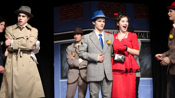 Un grupo de estudiantes en ropa vintage está frente a un edificio de ladrillo en el campus de la Lincoln High School.