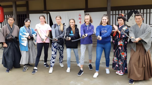 Un grupo de estudiantes de la Lincoln High School lleva ropa tradicional japonesa y ropa moderna de ocio en una habitación japonesa con puertas correderas.