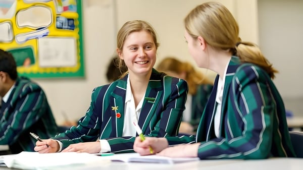 Dos estudiantes de la Lincoln Minster School están teniendo una conversación en un aula colorida.