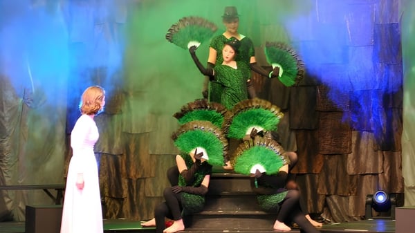 Estudiantes de Linden Hall presentan una obra de teatro con coloridos disfraces en un escenario imaginativo.