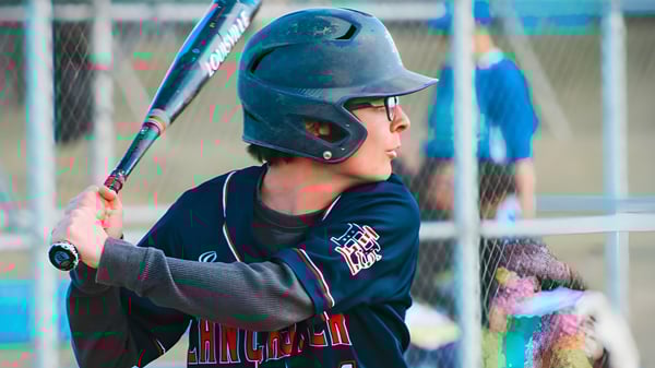 Un joven jugador de béisbol está en el bateador en la instalación deportiva de la Littlerock High School.