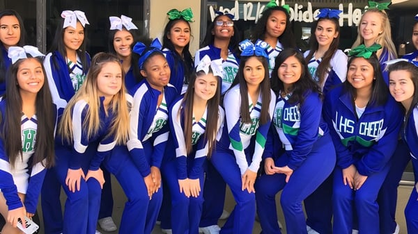 Un grupo de estudiantes en uniformes azules posan juntos en el campus de la Littlerock High School.