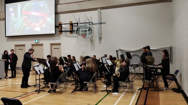 Estudiantes de la Livingstone School tocan en una orquesta en el escenario de un gimnasio.