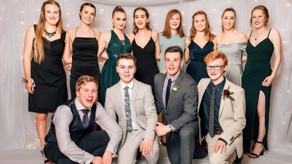 Un grupo de estudiantes de Logan Park High School posan juntos frente a un fondo blanco con ropa formal.