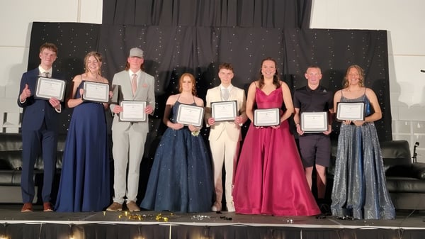 Estudiantes de la Lomond Community School están en el escenario sosteniendo premios frente a un cielo estrellado.