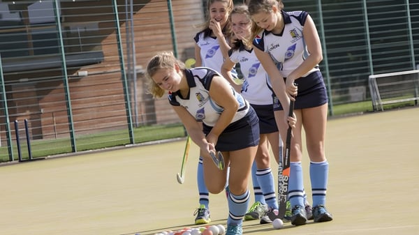 Un grupo de jóvenes atletas está de pie en el campo deportivo frente a un edificio de ladrillo en el campus de la Lomond School.