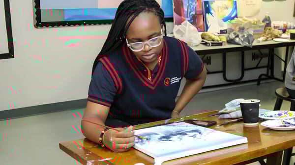 Una alumna de la London International Academy está concentrada en una mesa y trabaja en una obra de arte.