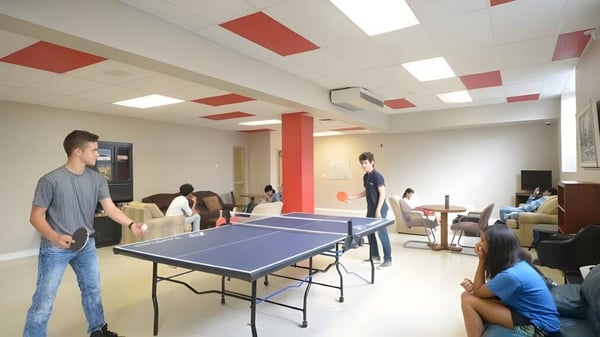 Un grupo de estudiantes juega al tenis de mesa en la luminosa sala de deportes de la London International Academy.
