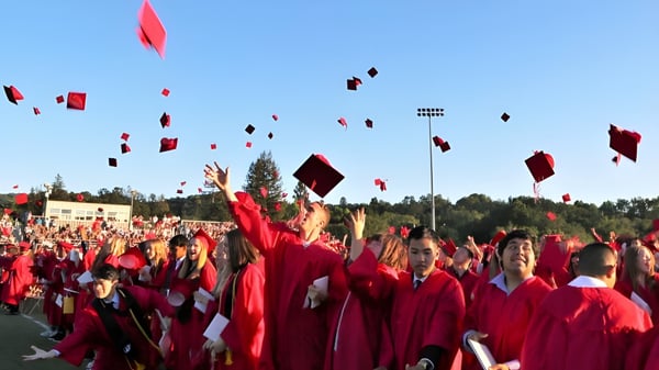 Estudiantes del London South Collegiate Institute lanzan sus birretes al aire durante la ceremonia de graduación.