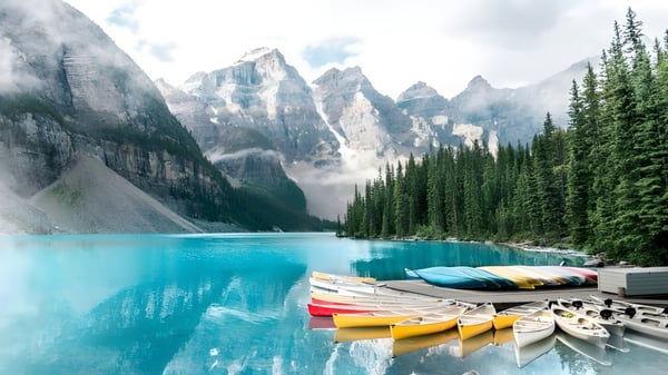 Un tranquilo lago alpino con coloridos kayaks en la orilla frente a montañas cubiertas de nieve cerca de la Longfields-Davidson Heights Secondary School.