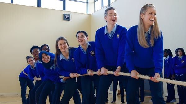 Un grupo de estudiantes en uniformes azules está sonriendo juntos en el Loreto College Mullingar.