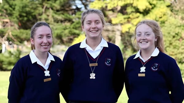 Tres alumnas de la Loreto High School Beaufort están sonriendo en un área parecida a un parque con árboles y zonas verdes.
