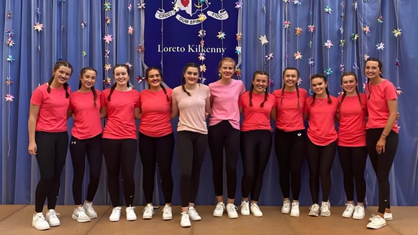 Un grupo de jóvenes estudiantes de la Loreto Secondary School está de pie en camisetas rojas frente a un fondo estrellado.