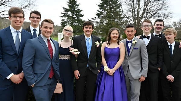 Un grupo de estudiantes de la Luckley House School está vestido formalmente frente a árboles y una zona de césped.