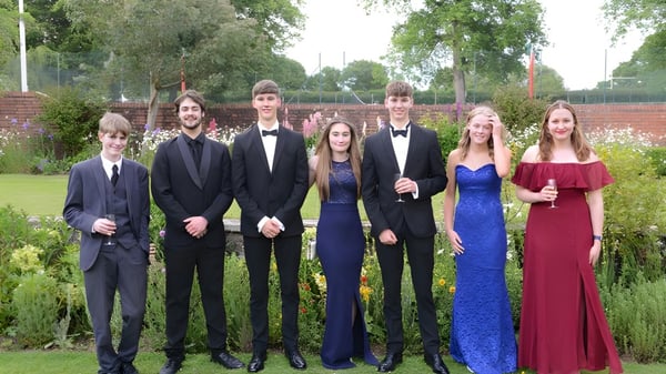 Un grupo de estudiantes de la Lucton School está junto en ropa formal en un jardín con árboles al fondo.