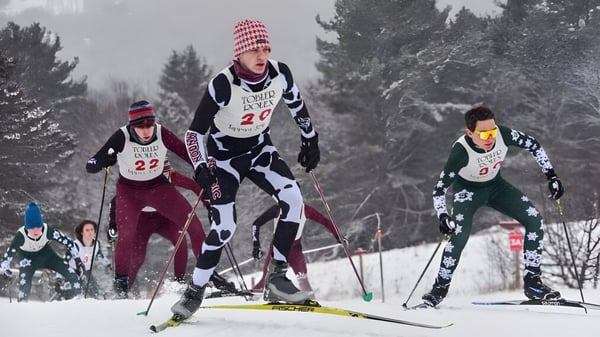 Estudiantes del Lyndon Institute participan en una carrera de esquí a través de un paisaje boscoso nevado.