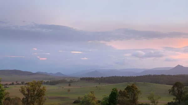 Paisaje con colinas, bosques y montañas al atardecer, sin relación directa con la Mabel Park State High School.
