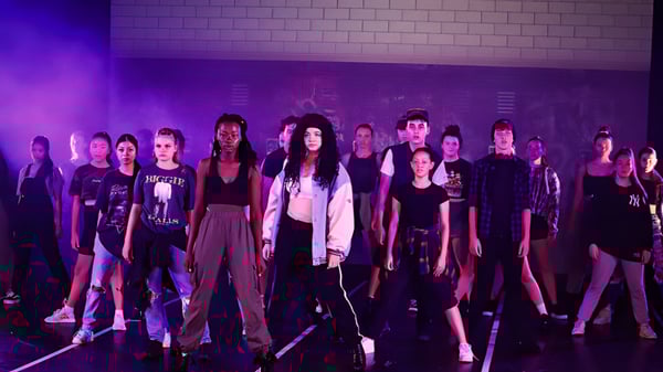 Un grupo de alumnas está en una habitación con poca luz en el campus de la MacGregor State High School.