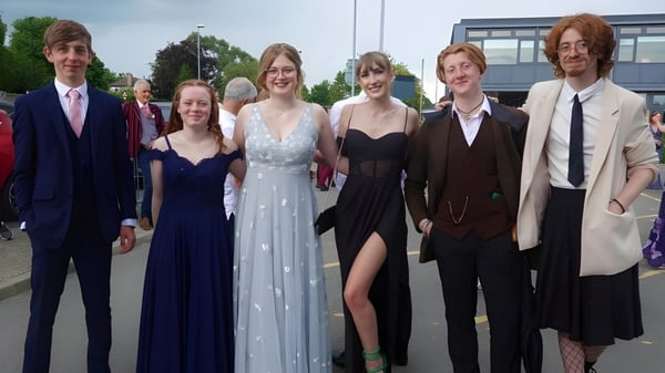 Un grupo de personas bien vestidas posan frente a un edificio en el campus del Macleans College.