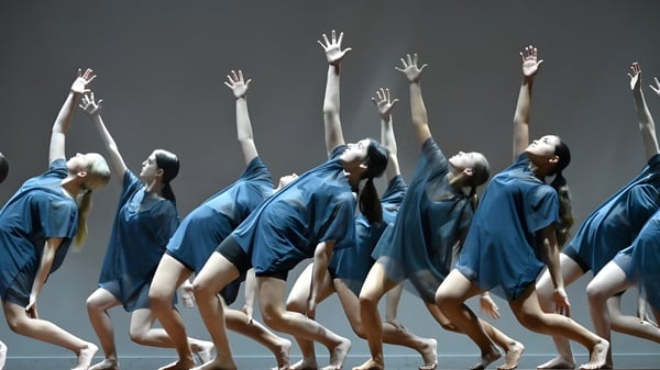 Estudiantes de Mahurangi College realizan una actuación de baile sincronizada en un escenario oscuro con trajes azules.