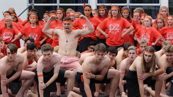 Un grupo de estudiantes de Mahurangi College lleva camisetas rojas y se reúne en el área exterior.