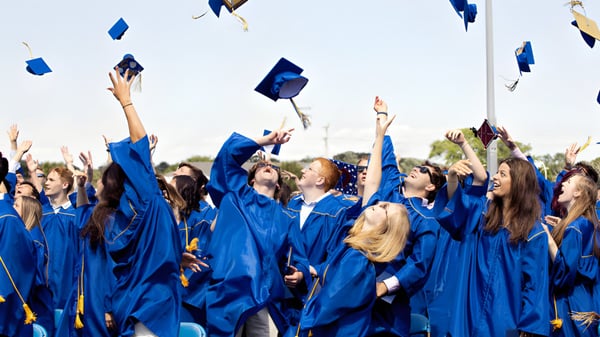 Un grupo de graduados de la Malanda State High School lanza sus sombreros azules al cielo.