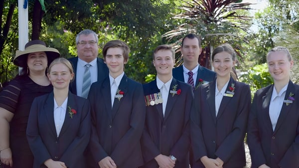 Los graduados de la Maleny State High School están en el área exterior verde con palmeras de fondo.