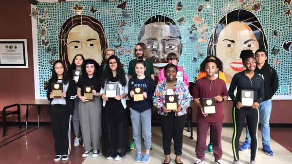 Un grupo de estudiantes está frente a un colorido mural en el campus de la Mallard Creek High School.