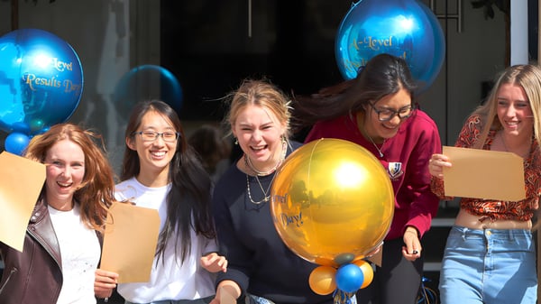 Un grupo de estudiantes de la Malvern St. James Girls' School celebra con globos de colores en un evento en interiores.