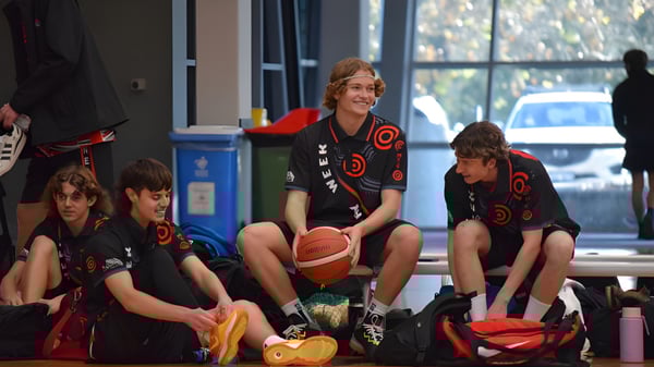 Estudiantes del Manea Senior College se preparan en una sala con baloncesto y vista al exterior para una actividad deportiva.