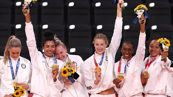 Atletas femeninas de la Mannahouse Christian Academy celebran con medallas de oro y girasoles frente a un fondo oscuro.