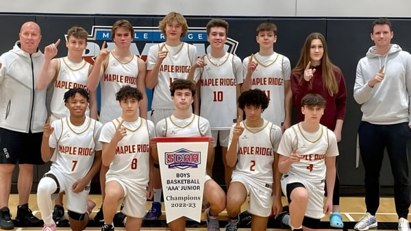 Un grupo de jóvenes jugadores y jugadoras de baloncesto posan frente al logo de Apple Ridge en el campus de la Maple Ridge Secondary School en Ontario.