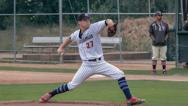 Un jugador de béisbol de la Maranatha High School en una camiseta a rayas lanza en el campo de béisbol.