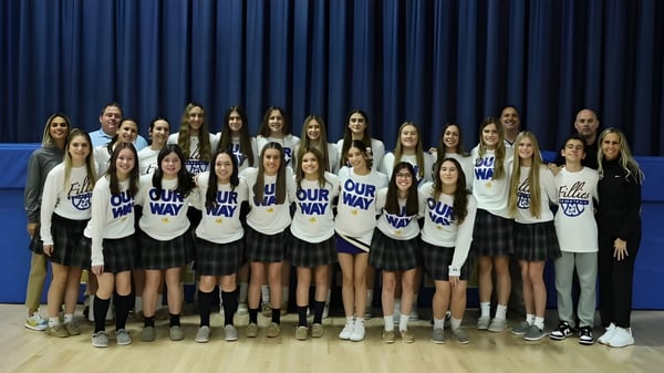Un grupo de estudiantes está de pie en uniformes uniformes frente a una cortina azul en el campus de la Marian Catholic High School.