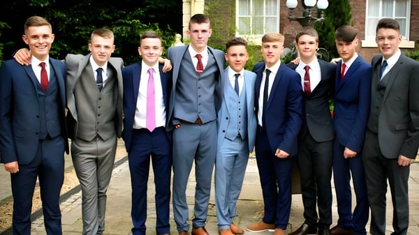 Un grupo de jóvenes en ropa formal está de pie frente a un edificio en el campus del Marian College.
