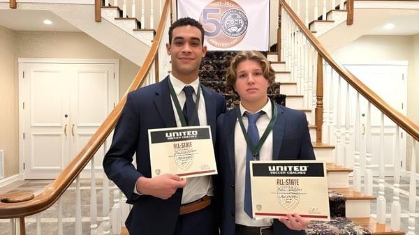 Dos estudiantes de la Marianapolis Preparatory School están en la escalera sosteniendo certificados de la organización United.