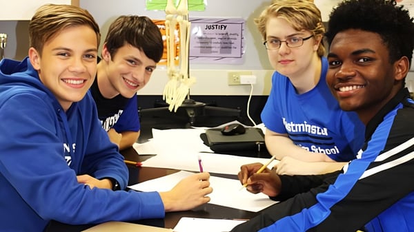Cuatro estudiantes del Marist College están sentados en una mesa y trabajan juntos en un aula.